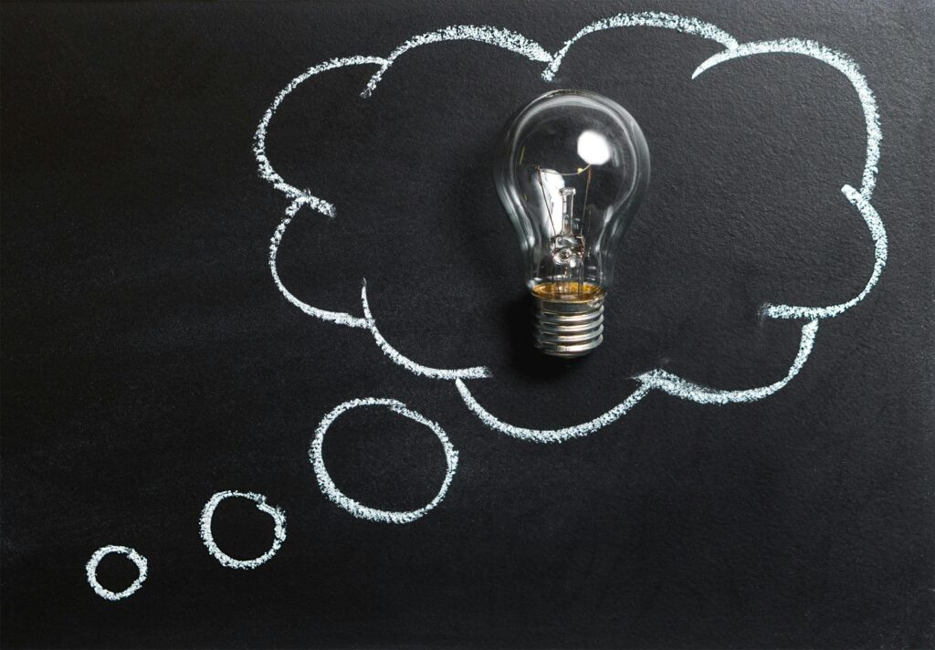 pexels-photo-355952-355952 Light bulb laying on chalkboard with drawn thought bubble, symbolizing creative ideas.
